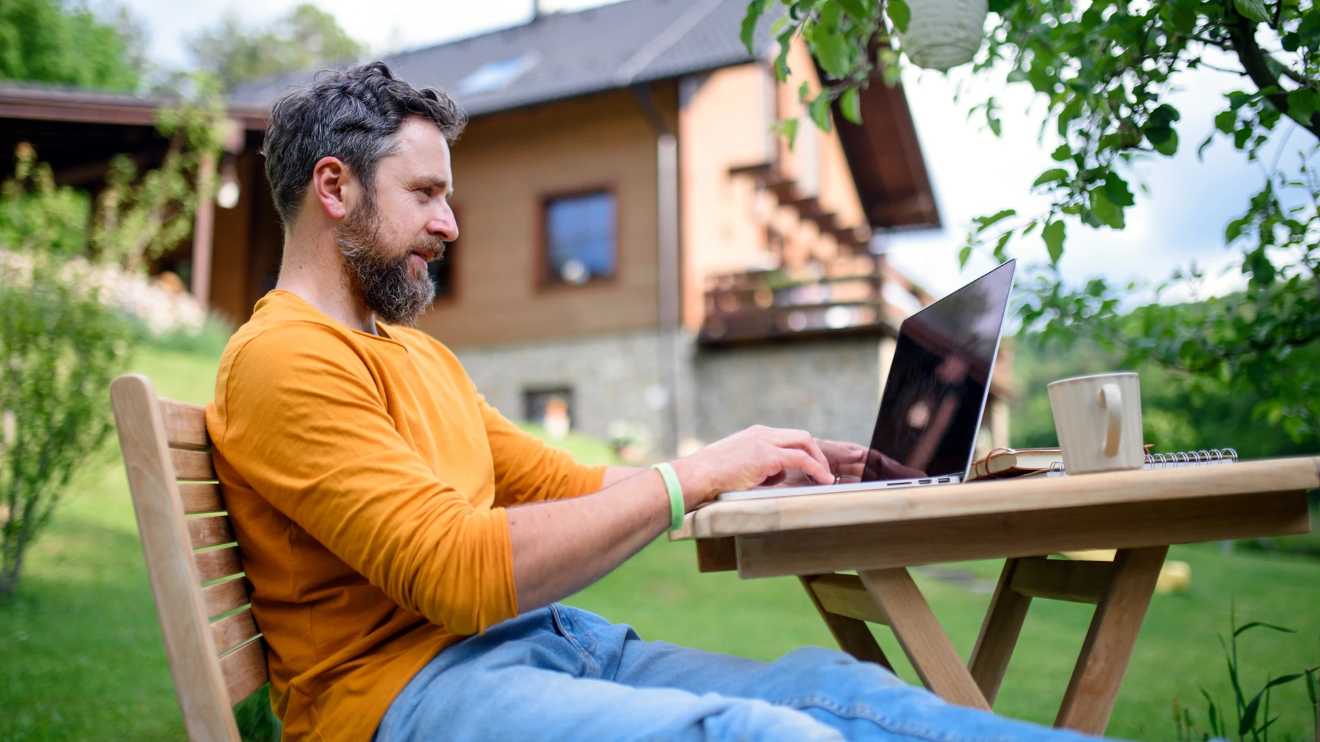 Gastbeitrag im Garten Lexikon - Schreib für uns 1 Gastbeitrag Gartenblog Schreib für uns - Mann schreibt an Laptop im Garten an einem sonnigen Holztisch